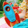 A close up of a red and blue wooden toy rocket with an astronaut looking through the window