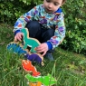 A child playing with a wooden turquoise diplodocus dinosaur toy figure, stacking them in the garden