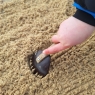 Coconut fork utensil shown to rake sand with childs hand