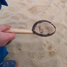 Coconut colinder held by child draining sand onto beach