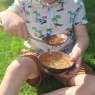 Child draining water through coconut colander into coconut bowl