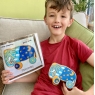 Boy holding elephant push along toy that he designed in one hand and original drawing in other hand