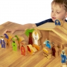 Angled view of child playing with wooden toy nativity sat on table top